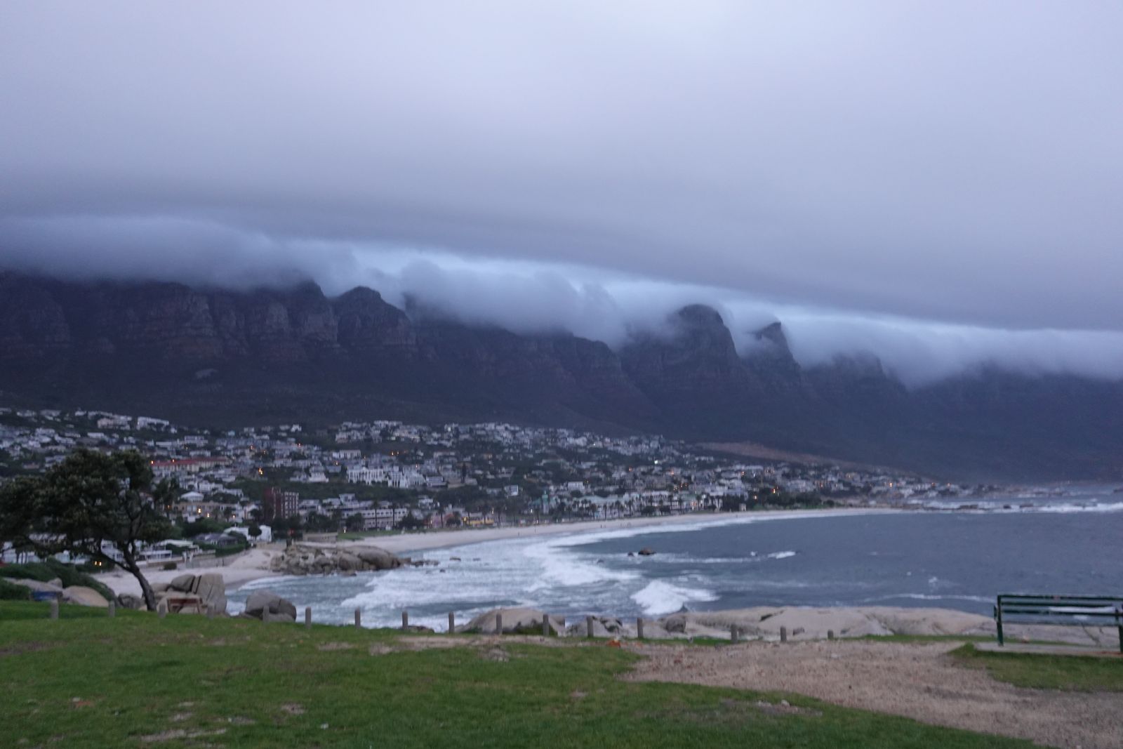 Low cloud pouring over mountains above a bay