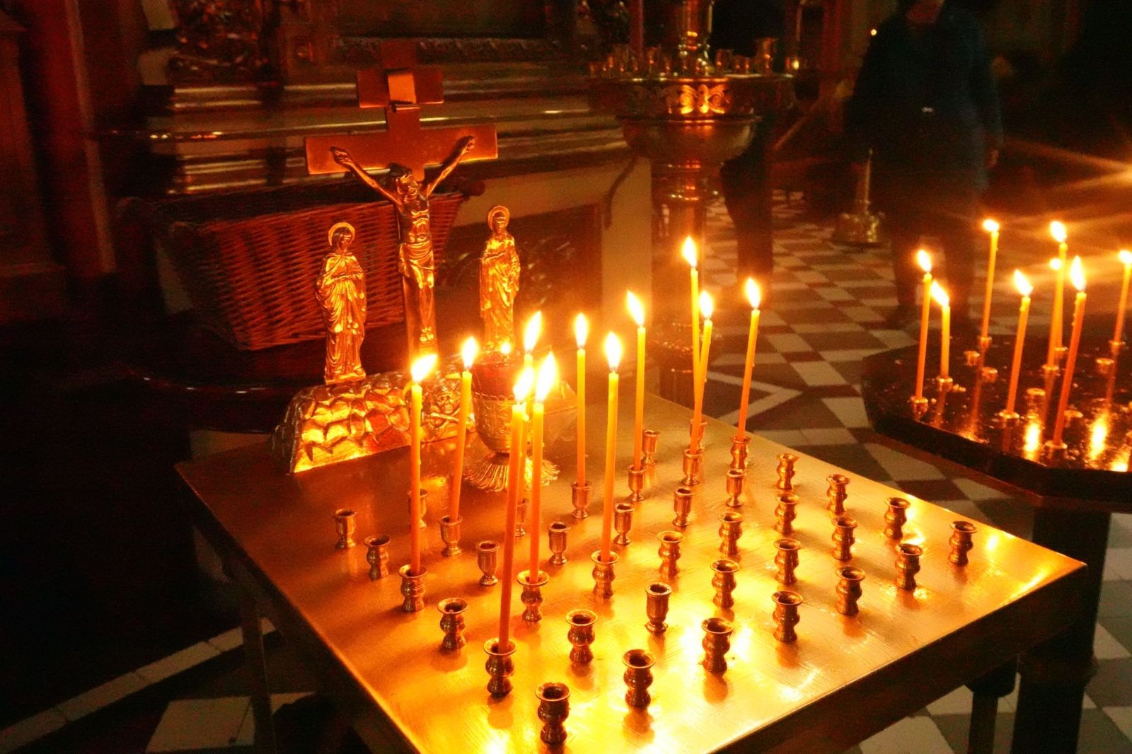 Thin beeswax candles burning on a brass stand in an Orthodox church