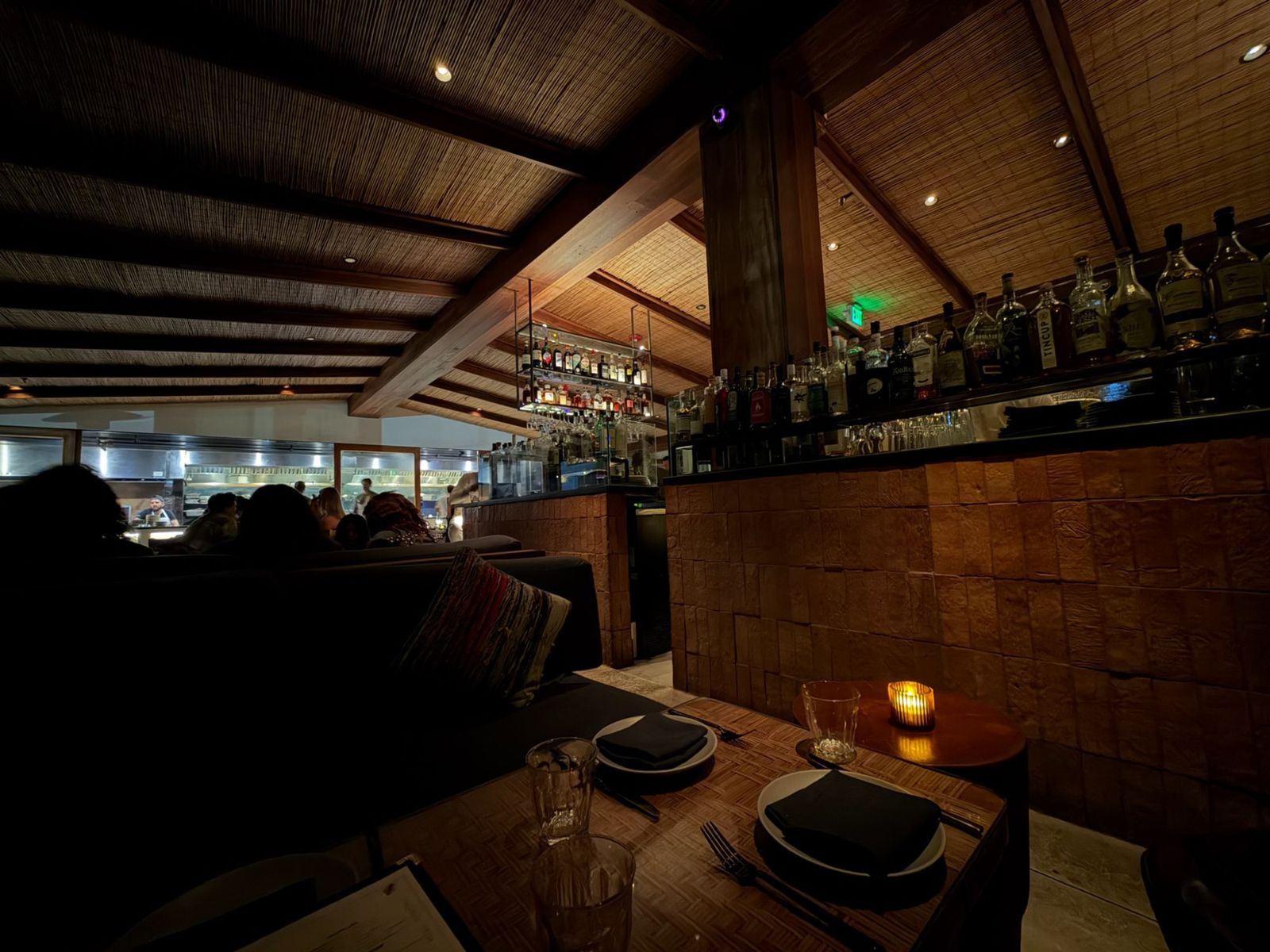 Candlelit table in a dark wood-beamed restaurant with a bar
