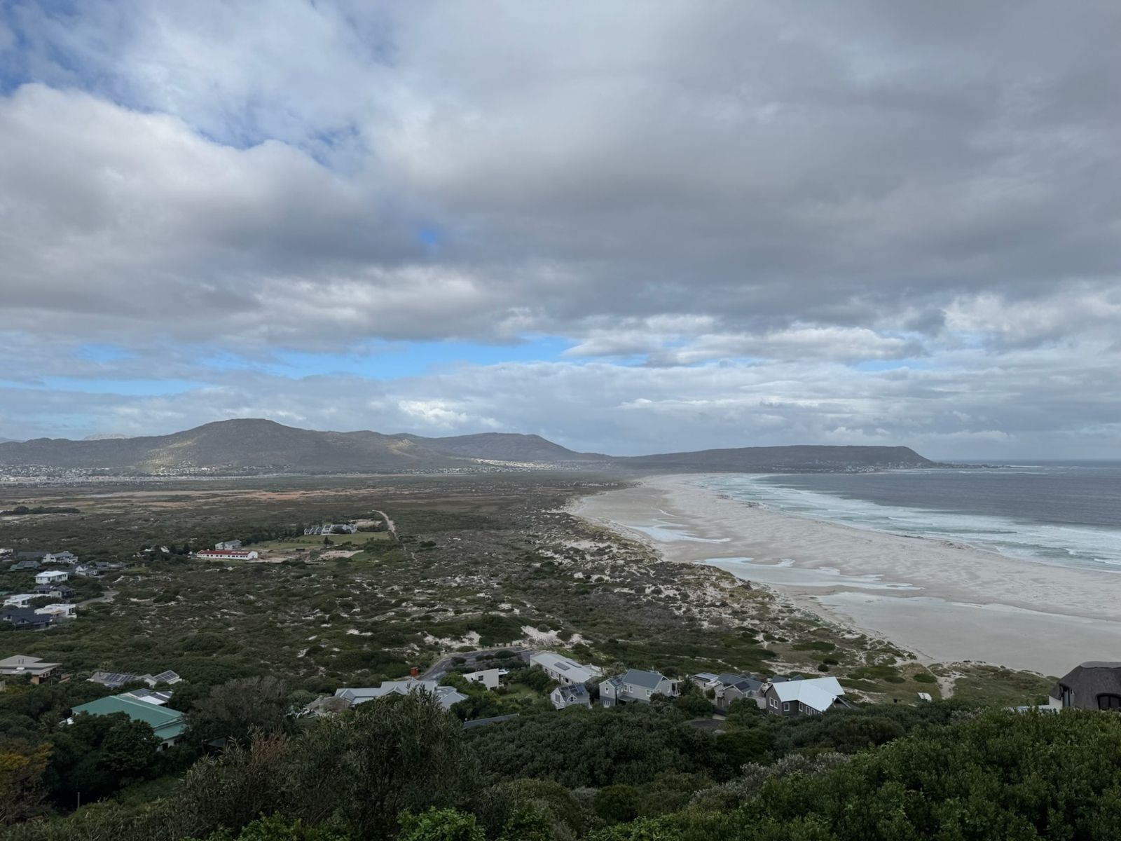 Long white beach and dunes under heavy clouds