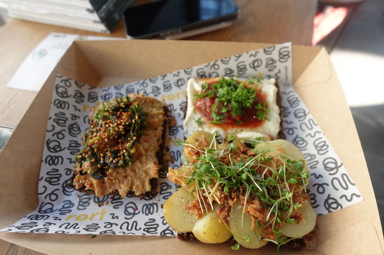 Three open-faced rye sandwiches in a paper tray
