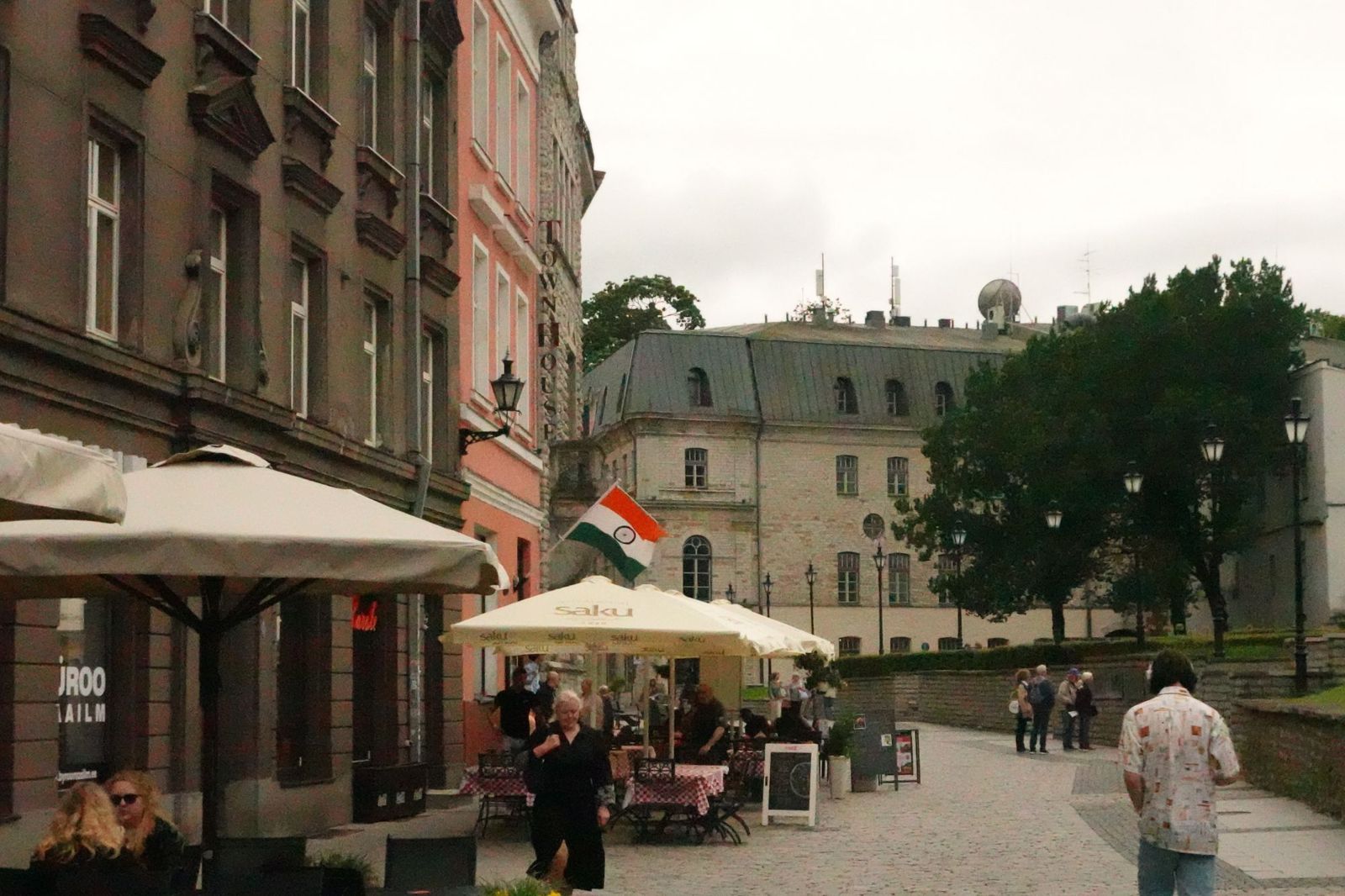 Cobbled street with cafe umbrellas and an Indian flag on a building