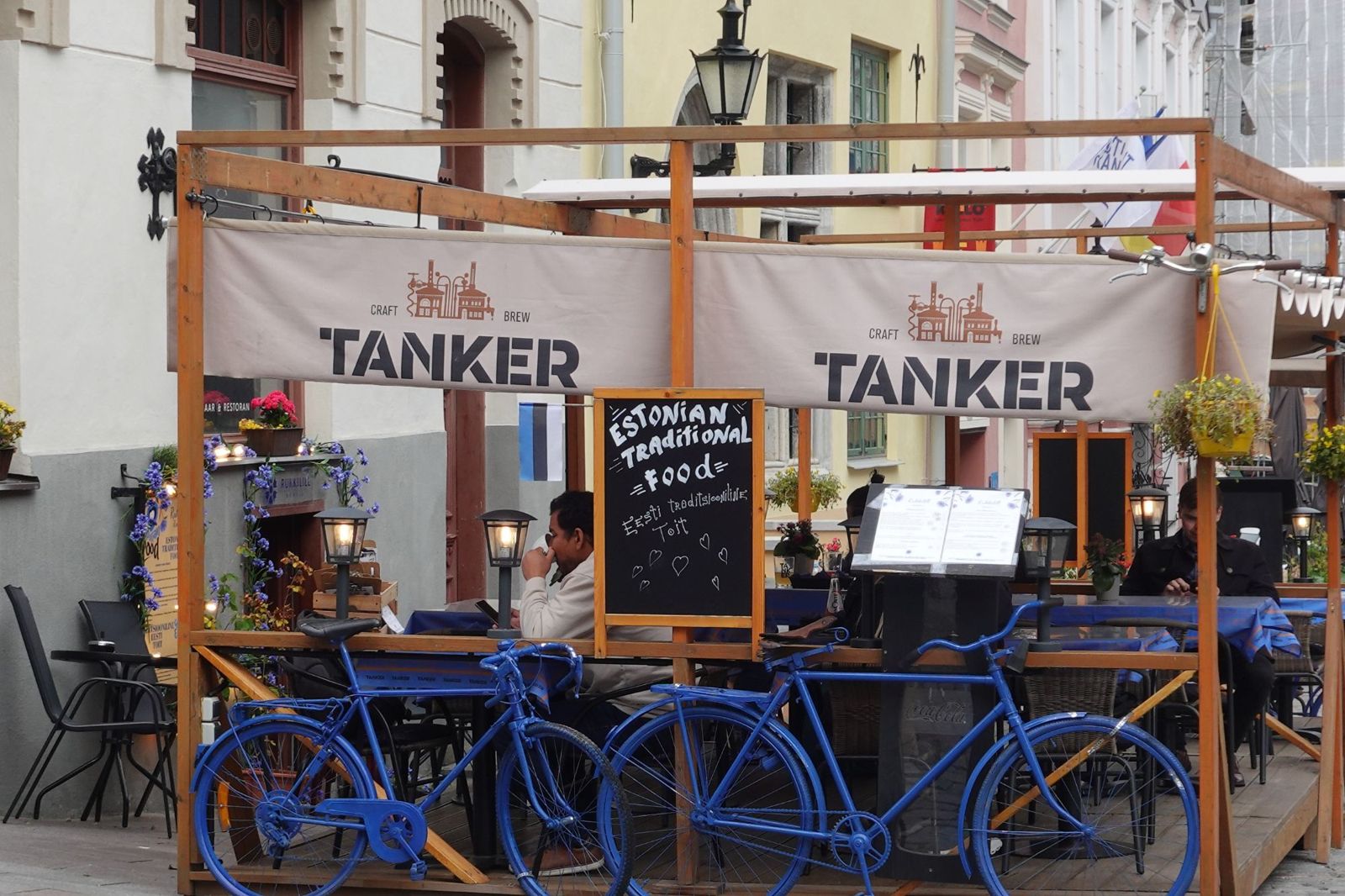 Blue bicycles outside a terrace restaurant with a chalkboard reading Estonian traditional food